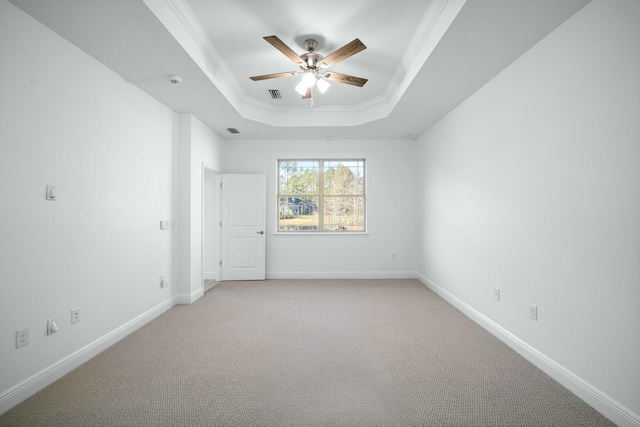 empty room with visible vents, crown molding, baseboards, a tray ceiling, and light carpet