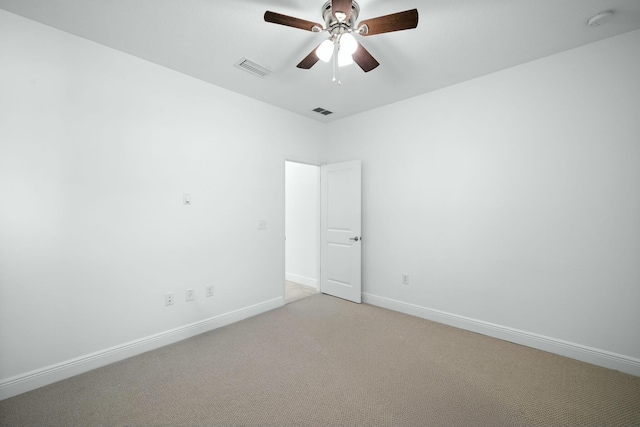 empty room featuring light carpet, visible vents, a ceiling fan, and baseboards