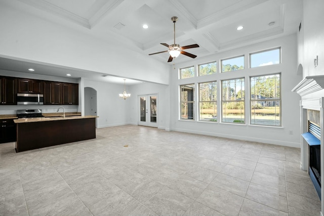 kitchen featuring a towering ceiling, a fireplace, open floor plan, and appliances with stainless steel finishes