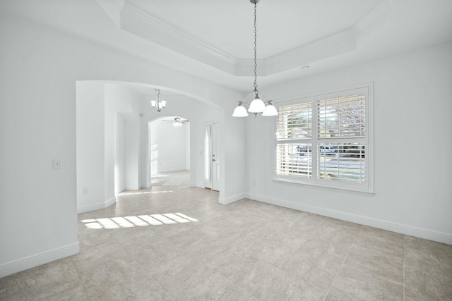 unfurnished dining area with ceiling fan, baseboards, a tray ceiling, ornamental molding, and arched walkways