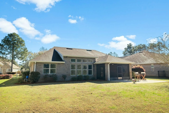 back of property with a yard, a patio, brick siding, and a sunroom