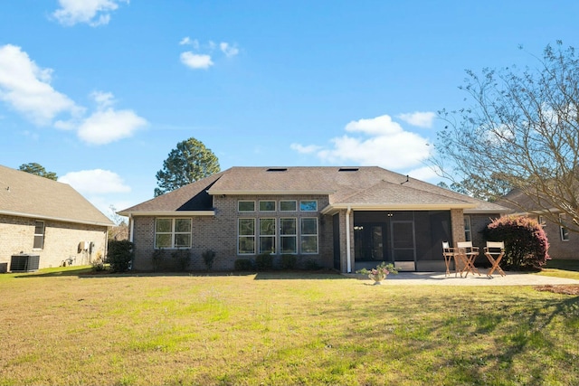 rear view of property with brick siding, central air condition unit, a yard, a sunroom, and a patio area