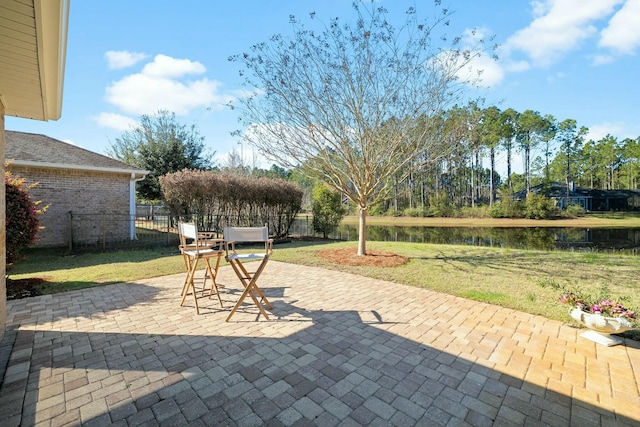 view of patio / terrace featuring fence and a water view