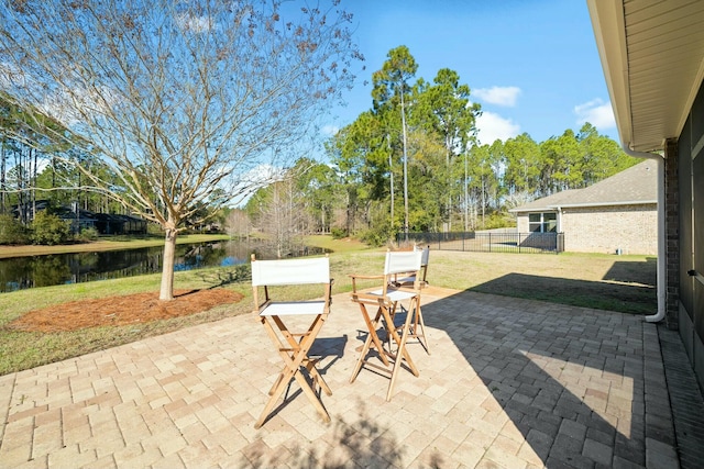 view of patio / terrace featuring fence and a water view