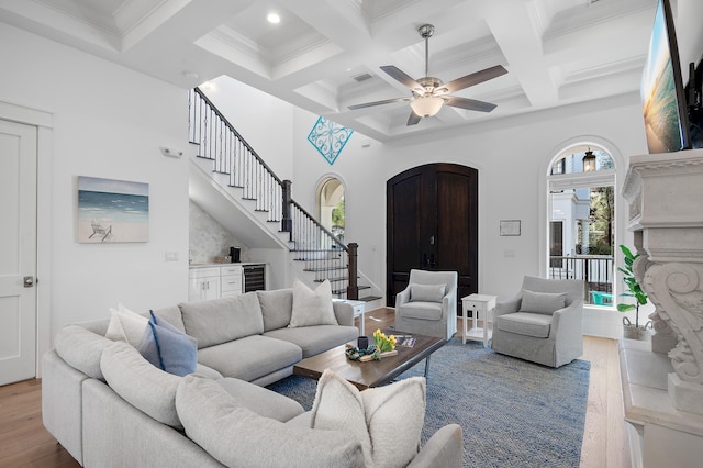 living room with wood finished floors, arched walkways, stairs, wine cooler, and a towering ceiling