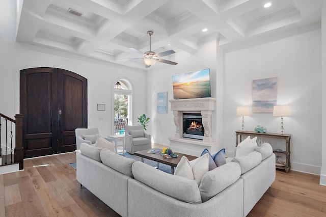 living room featuring hardwood / wood-style floors, beamed ceiling, visible vents, and a lit fireplace