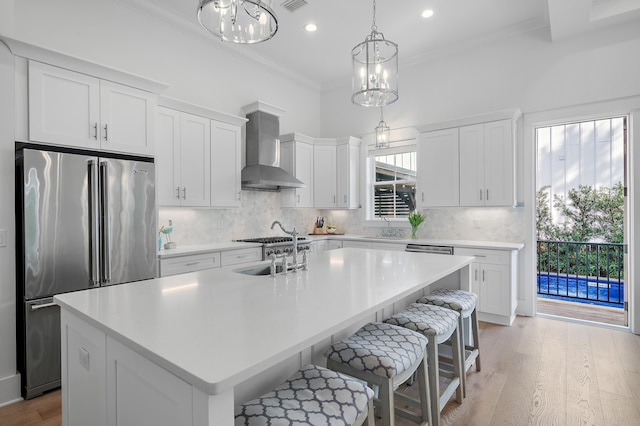 kitchen featuring a sink, crown molding, wall chimney range hood, decorative backsplash, and high end refrigerator