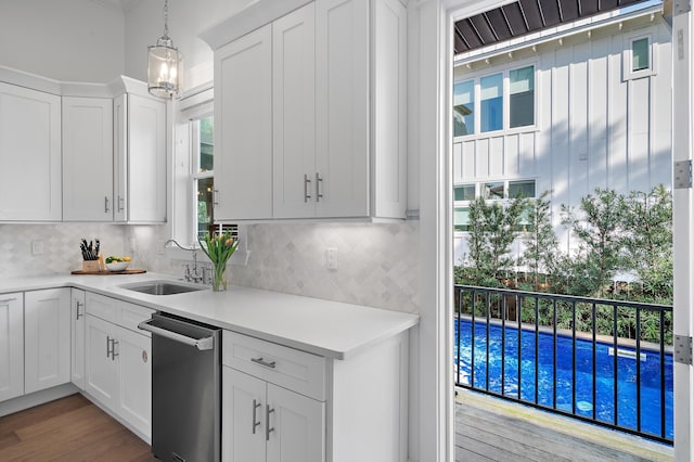 kitchen with dishwasher, decorative backsplash, white cabinetry, and a sink