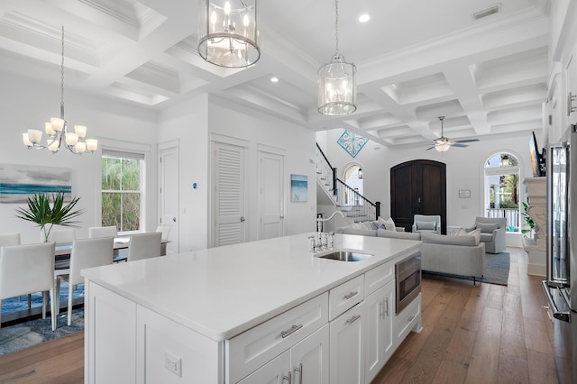 kitchen with dark wood-type flooring, ceiling fan with notable chandelier, a sink, appliances with stainless steel finishes, and white cabinets