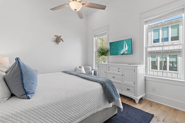 bedroom with baseboards, light wood-style flooring, and a ceiling fan