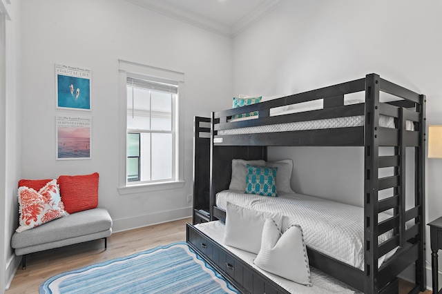 bedroom featuring baseboards, crown molding, and light wood-style floors