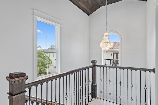 hall featuring an upstairs landing, wood ceiling, an inviting chandelier, and vaulted ceiling