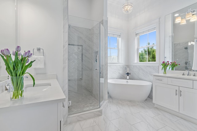 full bathroom with a freestanding tub, two vanities, a sink, an inviting chandelier, and a shower stall