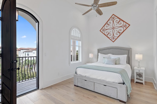 bedroom with a ceiling fan, wood finished floors, baseboards, arched walkways, and access to exterior