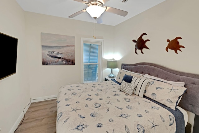 bedroom featuring wood finished floors, a ceiling fan, and baseboards