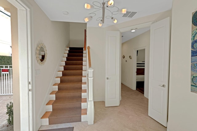 staircase with a notable chandelier, visible vents, and baseboards