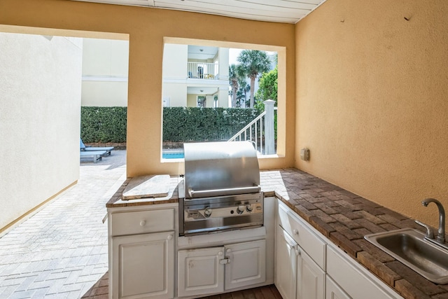 view of patio / terrace featuring exterior kitchen, a sink, and a grill