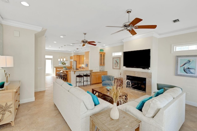 living room featuring baseboards, a tile fireplace, and crown molding