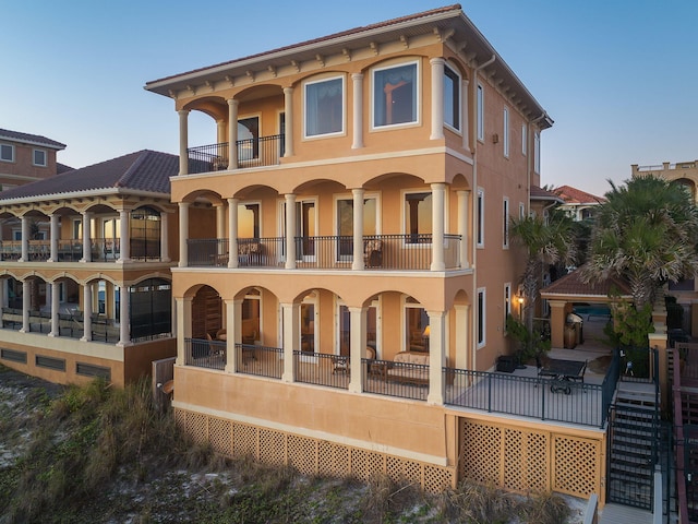 back of house with stucco siding and a balcony