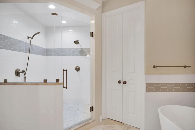 bathroom featuring a soaking tub, a shower stall, tile walls, and marble finish floor