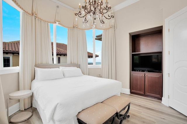 bedroom with an inviting chandelier, baseboards, light wood finished floors, and ornamental molding