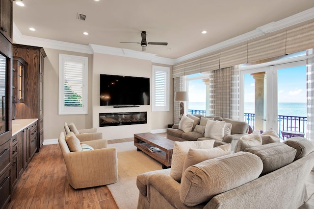 living area featuring baseboards, crown molding, ceiling fan, and wood finished floors