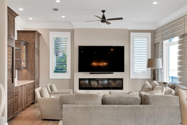 living area with light wood-type flooring, visible vents, ornamental molding, and a ceiling fan