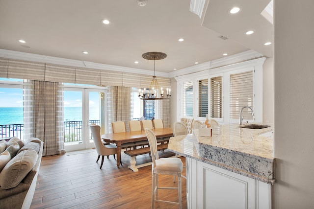 dining space featuring an inviting chandelier, light wood-style flooring, and ornamental molding