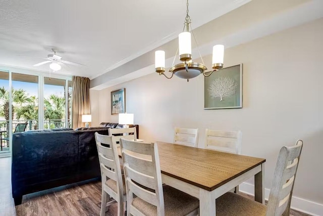 dining space with ceiling fan with notable chandelier, floor to ceiling windows, wood finished floors, and baseboards