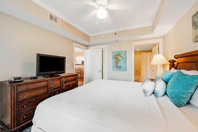 bedroom featuring a raised ceiling, visible vents, ceiling fan, and ensuite bathroom