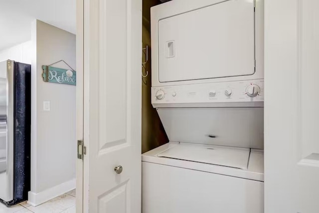 laundry room featuring laundry area, stacked washer / drying machine, and light tile patterned flooring