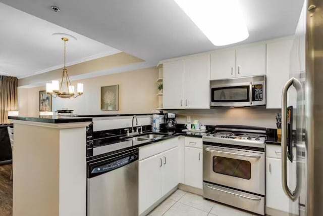 kitchen with dark countertops, appliances with stainless steel finishes, white cabinetry, a sink, and a peninsula