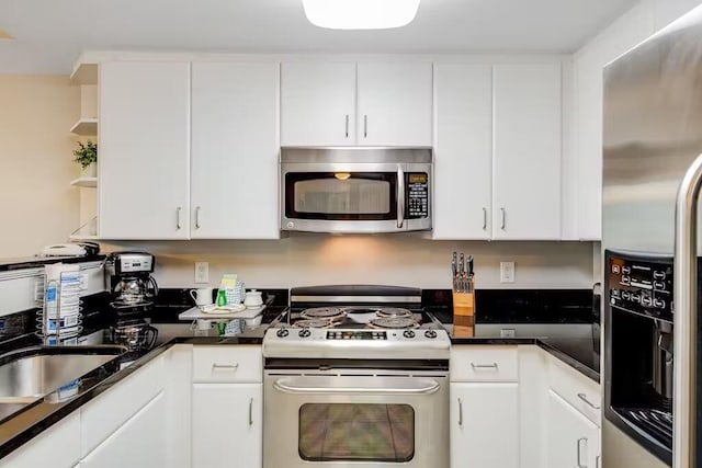 kitchen with stainless steel appliances, white cabinetry, a sink, and open shelves