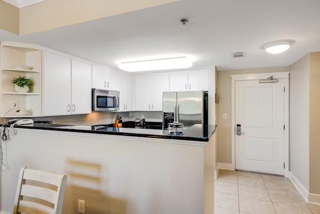 kitchen featuring light tile patterned floors, a peninsula, visible vents, appliances with stainless steel finishes, and dark countertops