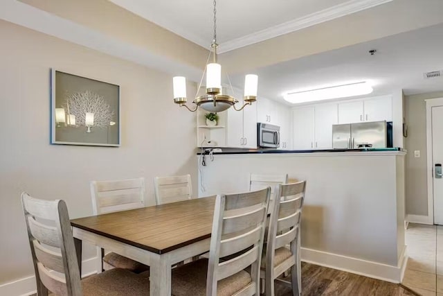 dining room featuring baseboards, visible vents, wood finished floors, an inviting chandelier, and crown molding