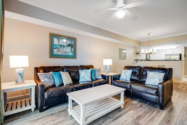 living room with ceiling fan with notable chandelier, light wood-style floors, and crown molding