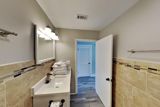 bathroom featuring visible vents, wainscoting, wood finished floors, and tile walls