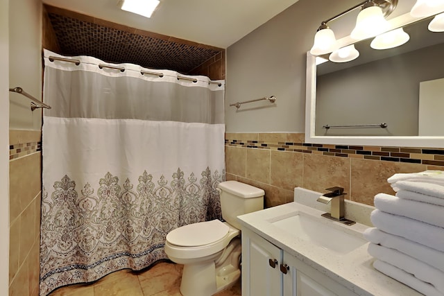 full bathroom featuring toilet, a shower with curtain, tile patterned floors, vanity, and tile walls