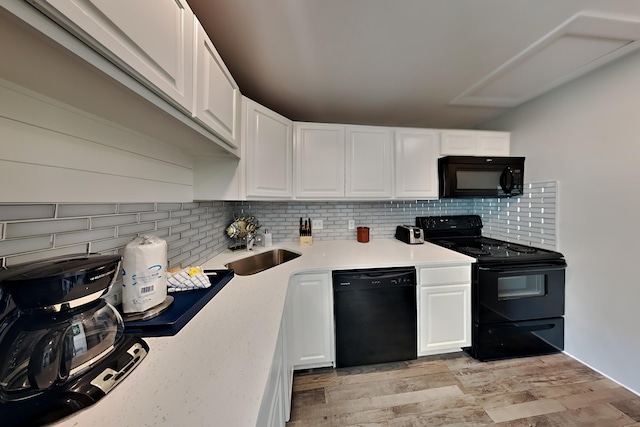 kitchen featuring light countertops, backsplash, white cabinetry, a sink, and black appliances