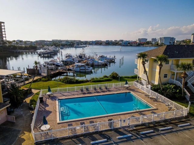 community pool featuring a patio area, a water view, and fence