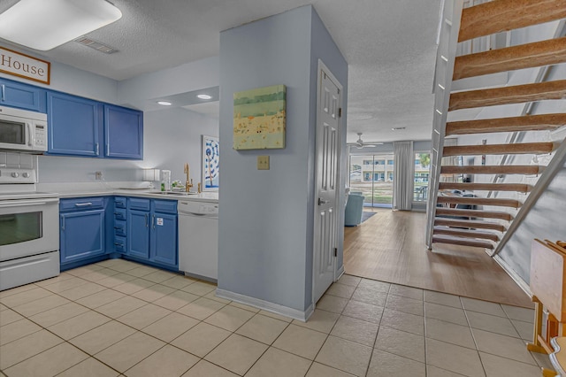 kitchen with white appliances, visible vents, light countertops, blue cabinetry, and light tile patterned flooring