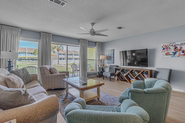 living room with a ceiling fan, visible vents, a textured ceiling, and wood finished floors