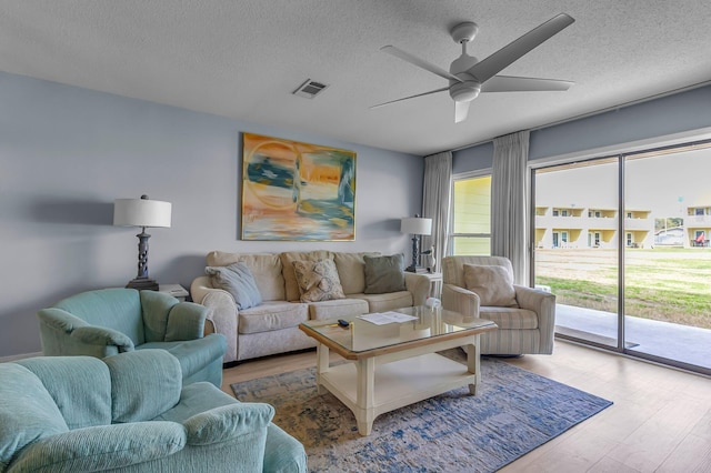 living room with visible vents, ceiling fan, a textured ceiling, and wood finished floors