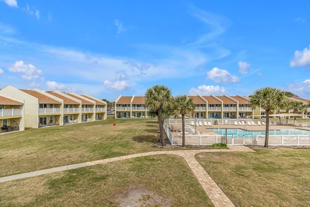 community pool featuring a residential view, a lawn, and fence