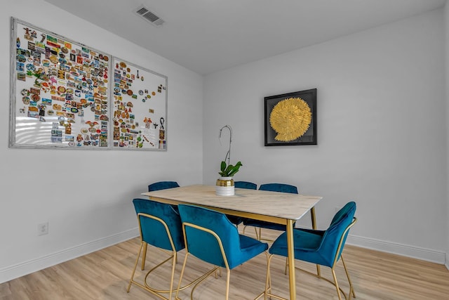 dining area featuring wood finished floors, visible vents, and baseboards