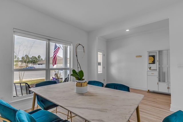 dining room featuring light wood-style floors, baseboards, crown molding, and recessed lighting