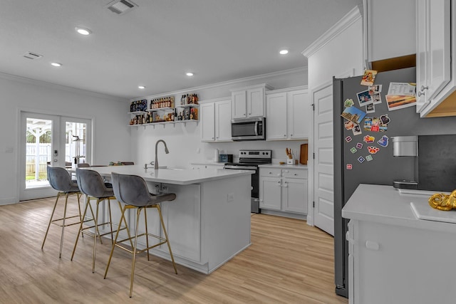 kitchen with appliances with stainless steel finishes, a kitchen breakfast bar, light countertops, crown molding, and a sink