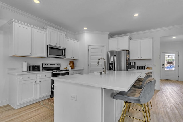 kitchen with light wood-style floors, a kitchen island with sink, white cabinetry, and stainless steel appliances