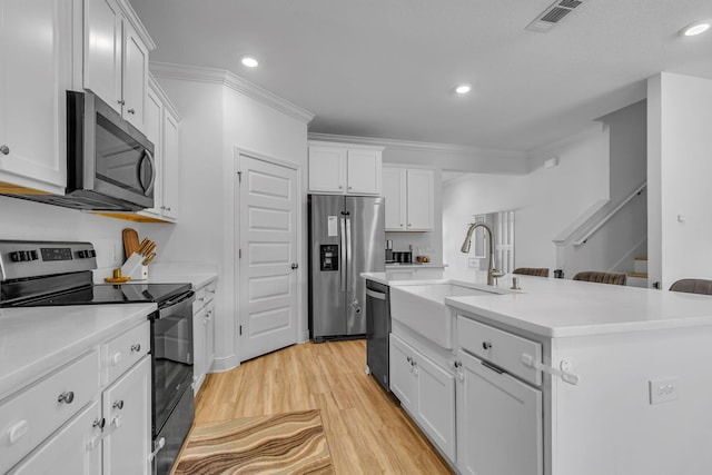 kitchen featuring stainless steel appliances, a sink, visible vents, white cabinetry, and an island with sink