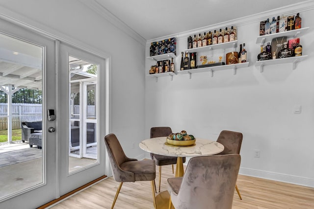 dining room featuring ornamental molding, light wood-type flooring, and baseboards